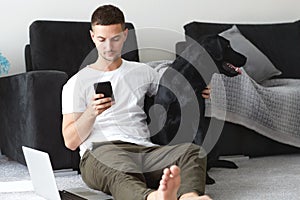 Freelancer guy with laptop and dog is working at home in quarantine to coronavirus infection