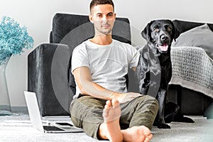 freelancer guy sitting at home working with a dog in an embrace, black labrador.