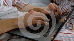 Freelancer hands typing laptop keyboard in pajamas closeup. Man working late