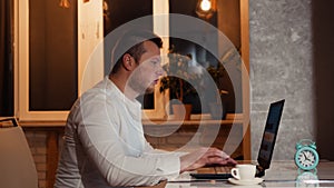 A freelancer at home with a cup of coffee works at home at his desk, typing on a computer keyboard. Office worker drinking coffee