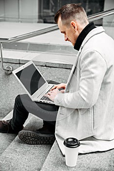 Freelancer with a laptop on the steps outdoors