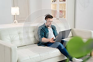 Freelancer listens audio headphones sit on sofa