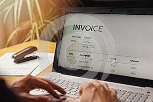 freelancer make an invoice on laptop computer at home office. business accounting