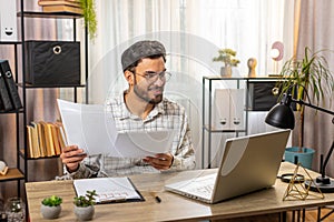 Freelancer man accountant works with financial graph documents calculate taxes for charts at office
