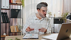 Freelancer man accountant works with financial graph documents calculate taxes for charts at office