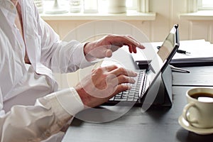 Freelancer man sits at a table and takes notes in a laptop.