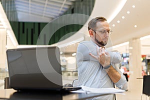 Freelancer man stretching arms while working at laptop