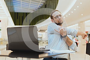 Freelancer man stretching arms while working at laptop