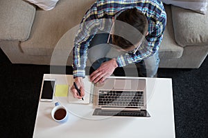 Freelancer man working working at home, making notes in notebok. photo