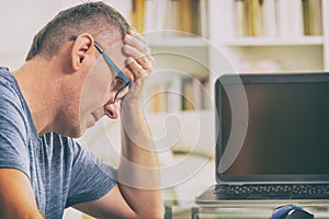 Freelancer man at workplace in office holding his head on hands