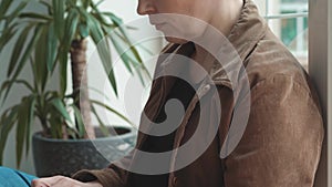 Freelancer mature gray haired woman working on laptop sitting leaning back against the window. Business concept. Camera