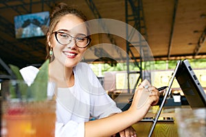 Freelancer mixed race woman hand pointing with stylus on convertible laptop screen in tent mode. Asian caucasian girl
