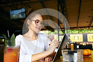 Freelancer mixed race woman hand pointing with stylus on convertible laptop screen in tent mode. Asian caucasian girl