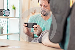 Freelancer playing mobile video game on smartphone in home office