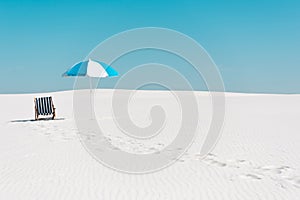 Freelancer on sandy beach with laptop against clear blue sky