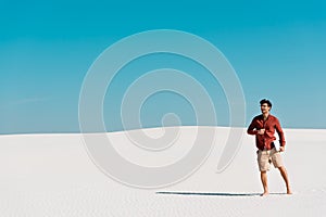 Freelancer on sandy beach with laptop against clear blue sky