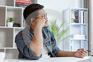 Freelancer is thinking idea or trying to solve a problem. A man is working on his laptop.