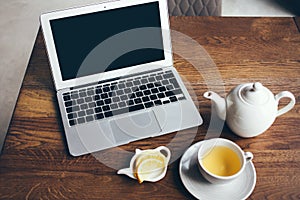 Freelancer is using laptop computer for remote work while having breakfast dinner at modern restaurant.