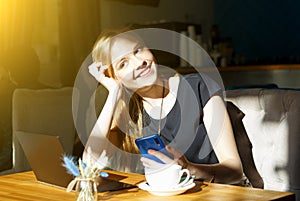 Freelancer woman working online on laptop and cellphone while resting in cafe photo