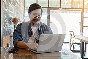 Freelancer is working on his laptop at cafe. A man is typing keyboard on laptop.