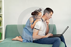 Freelancer working at home in comfortable conditions. Man trying to work, child prevents his father to work