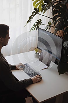 Freelancer is working from home. Developer man is coding using screen and tablet