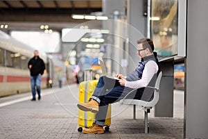 Freelancer working with a laptop in a train station while is waiting for transport