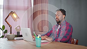freelancer working remotely from home, portrait of african american man with laptop in living room