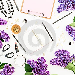 Freelancer workspace with diary, lipstick, scissors, branches of lilac and accessories on white background. Flat lay, top view