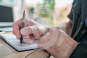 Freelancer writing notes in a notebook while working in home office