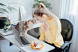 Freelancer young woman eating healthy food when working from home. Woman eating Healthy Grain Snacks and fruits while