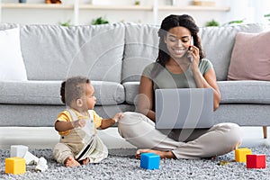 Black Woman Working On Laptop And Taking Care Of Her Infant Child