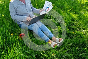 Freelancing outdoors in the garden. A woman with a laptop works on the lawn. The idea of effective business management in nature