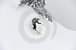 freeride male skier with go-pro camera on his helmet sliding down snow covered slope.