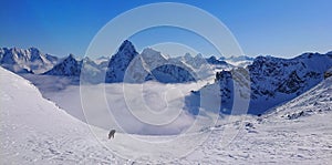 Freeride snowboarder carves down the snowy mountain towards the cloudy valley