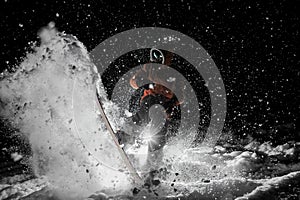 Freeride snowboarder jumping on the board in snow at night