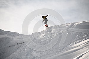 Freerider in anorak jumping on a snowboard in mountains