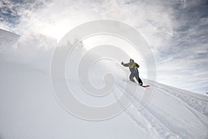 Freerider in anorak rides on a snowboard in mountains