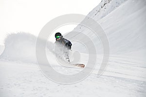 Freerider in full equipment rides on a snowboard in mountains