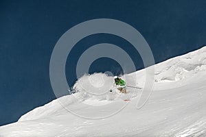 Freerider skier in bright ski suit slides in beautiful mountains landscape.