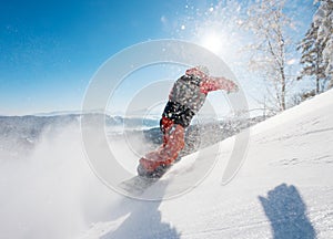 Freerider snowboarder riding the slope on a sunny winter day in the mountains