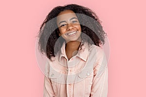 Freestyle. African girl in denim jacket standing isolated on pink smiling cheerful