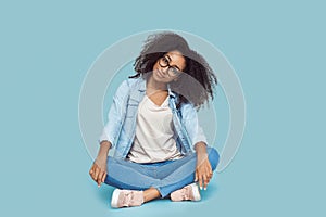 Freestyle. African girl in glasses sitting  on gray posing smiling confident