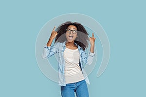 Freestyle. African girl in glasses standing isolated on gray pointing up copy space smiling surprised