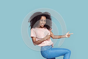Freestyle. African girl standing  on gray pointing aside at copy space posing smiling playful