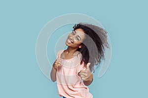 Freestyle. African girl standing isolated on gray thumbs up smiling cheerful