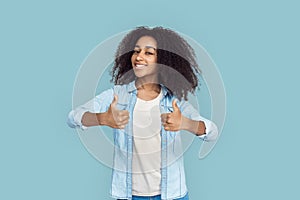 Freestyle. African girl standing isolated on gray thumbs up smiling satisfied
