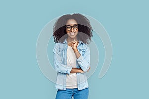 Freestyle. African girl wearing glasses standing  on gray touching chin smiling toothy
