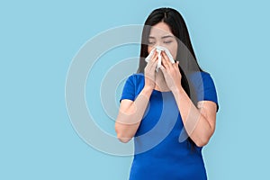 Freestyle. Chinese woman standing isolated on grey blowing nose into tissue concerned