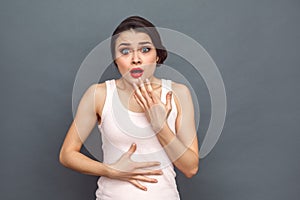 Freestyle. Woman standing isolated on grey looking camera shocked